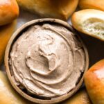 overhead view of texas roadhouse honey cinnamon butter in a bowl surrounded by rolls.