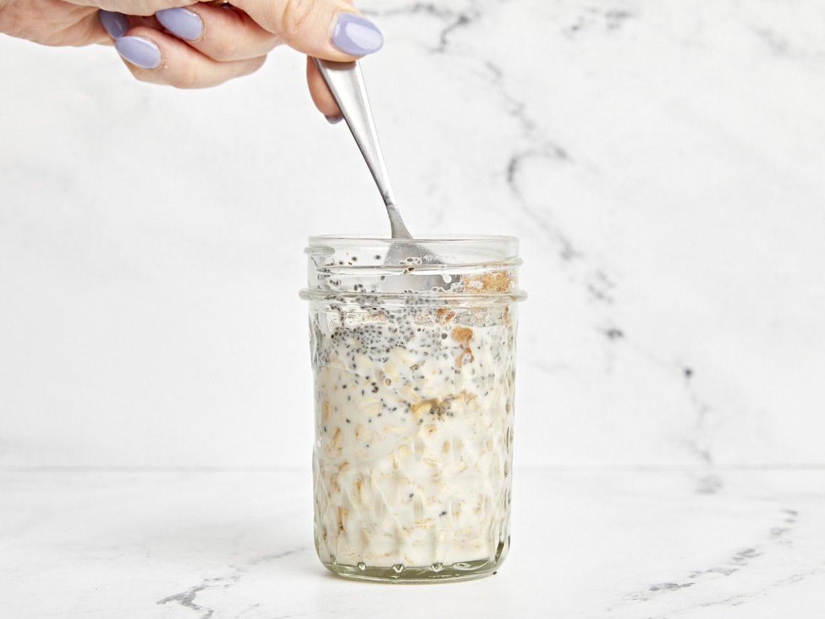 Ein Löffel zum Vermischen der Zutaten für Overnight Oats in einem Einmachglas