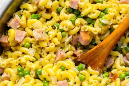 ham and pea pasta in a pot with a wooden spoon.