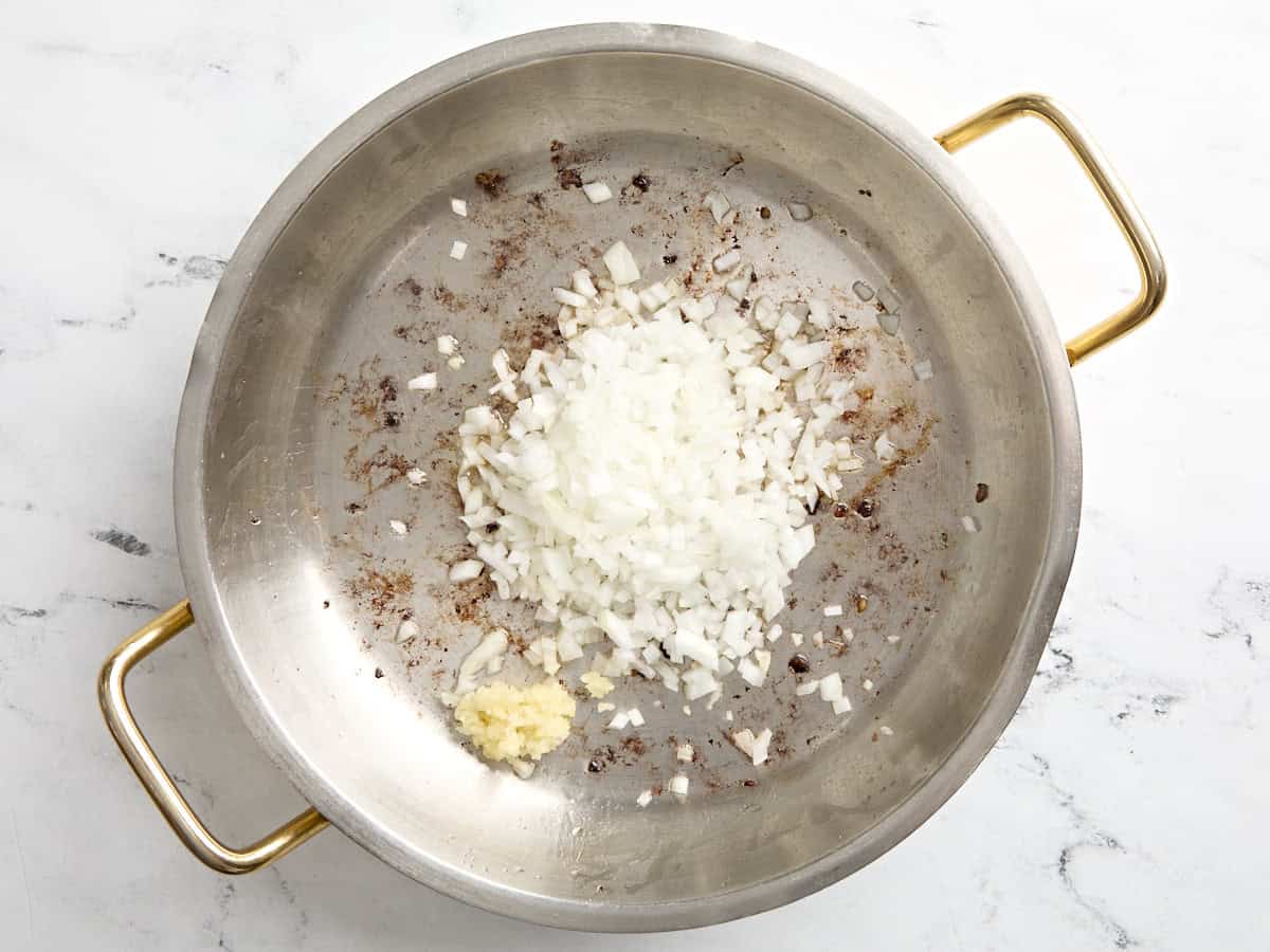 Gewürfelte Zwiebeln und gehackter Knoblauch in die Pfanne geben.