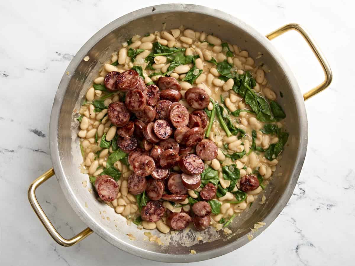 Hühnerwurst mit weißen Bohnen und Spinat zurück in die Pfanne geben.