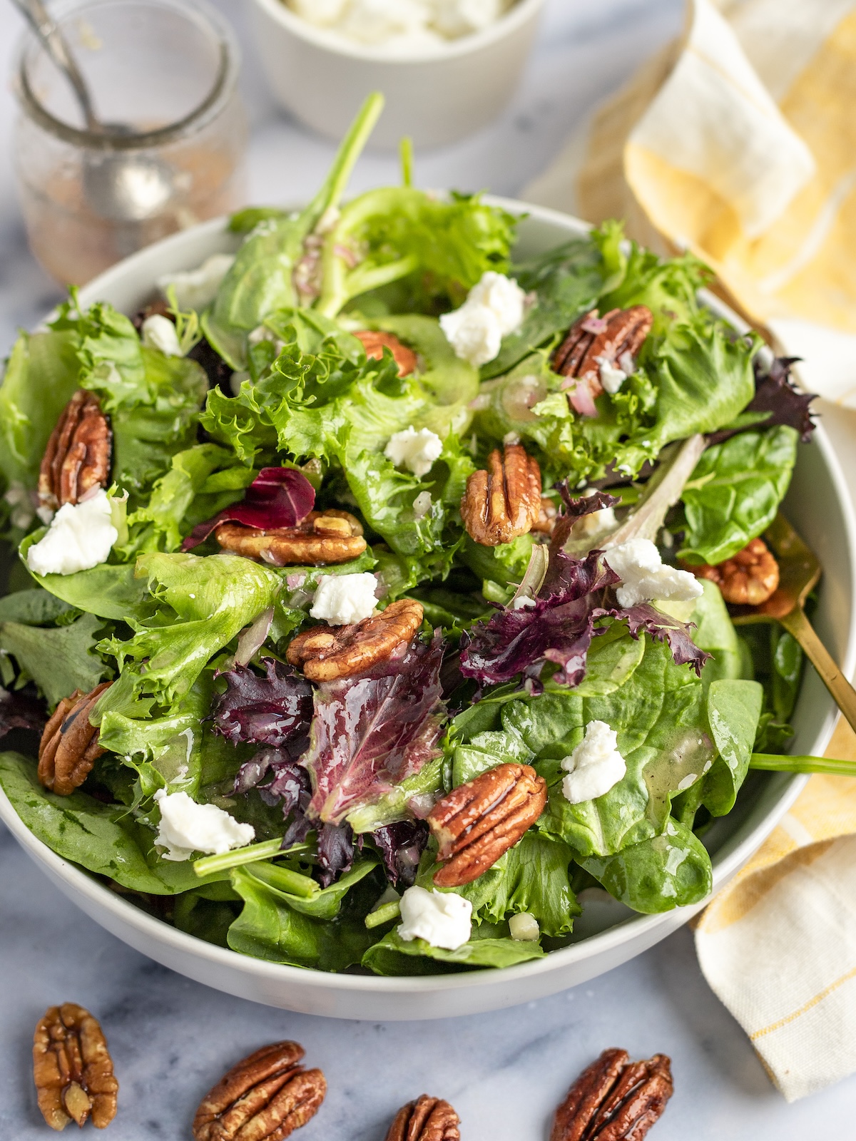 Grüner Salat mit Ziegenkäse, Pekannüssen mit Ahornglasur und Ahorn-Dijon-Vinaigrette mit gestreifter Leinenserviette