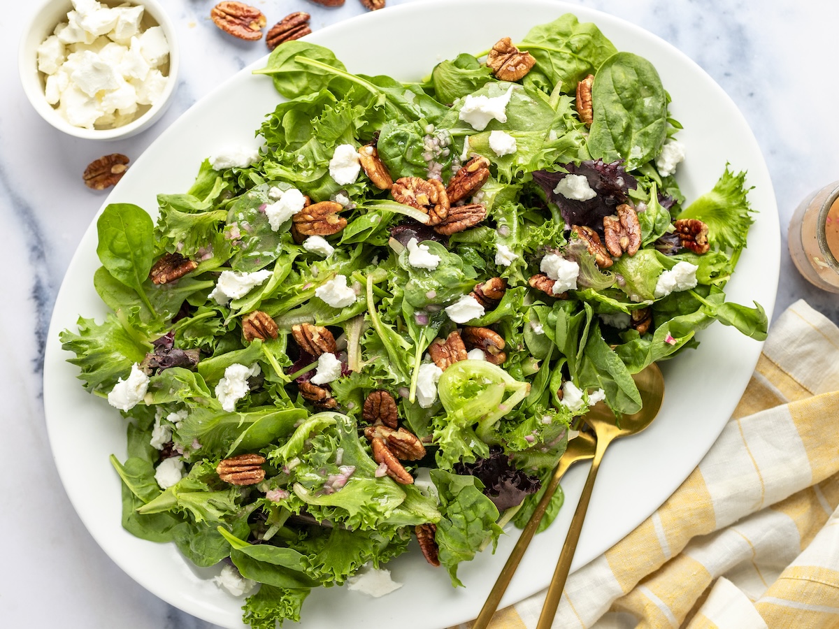 Grüner Salat mit Ziegenkäse, Pekannüssen mit Ahornglasur und Ahorn-Dijon-Vinaigrette mit gestreifter Leinenserviette