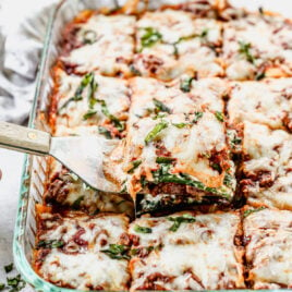 Ein Stück Zucchini-Lasagne mit einem Spatel herausnehmen