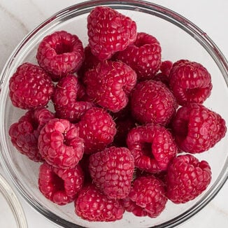 Himbeeren und weiße Schokoladenstückchen in Schüsseln. 