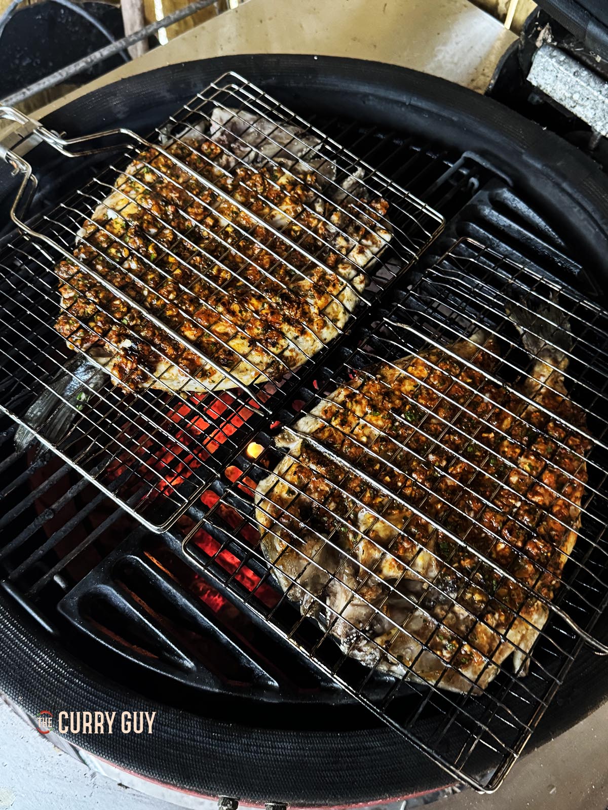 Grillen des Fisches im Fischkorb über heißer Holzkohle.