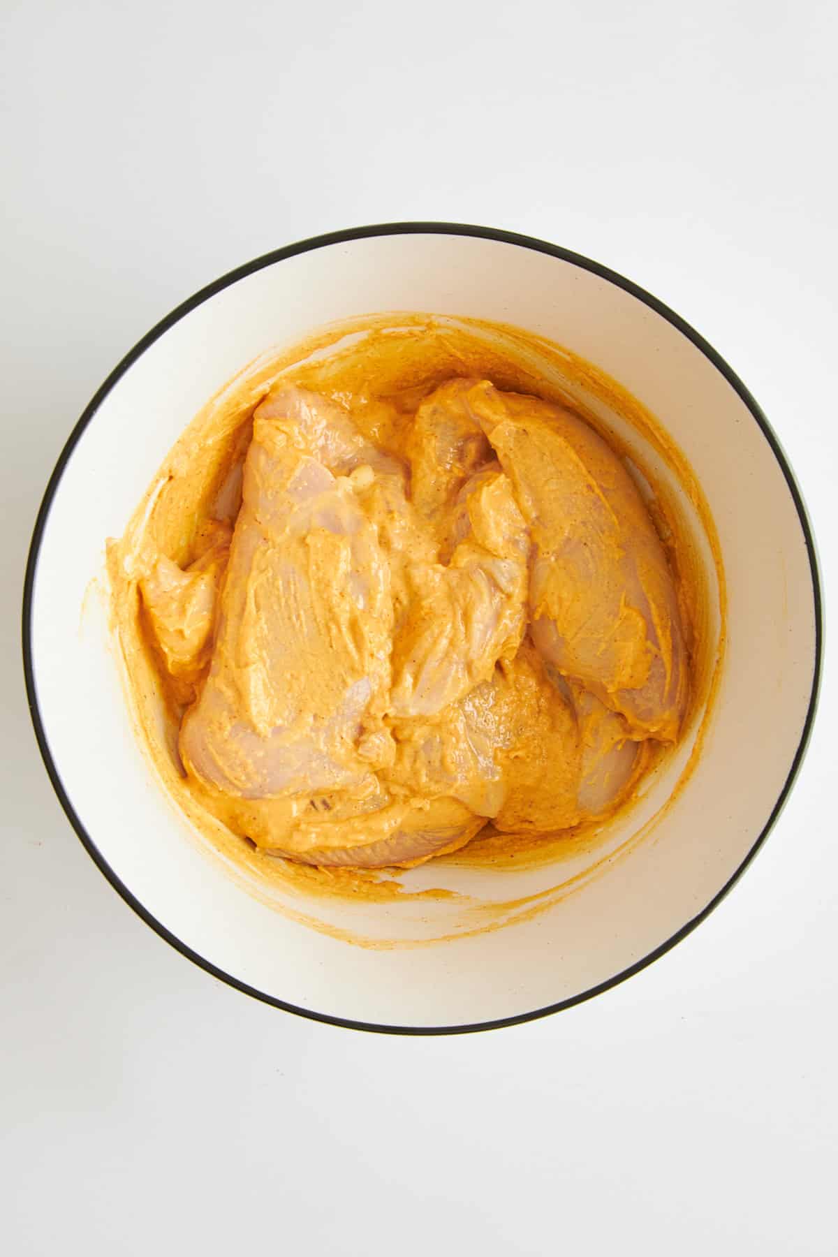 Rohes Hühnchen mit Hummus-Marinade in einer Schüssel. 