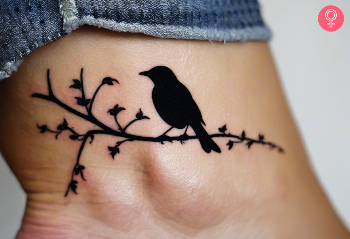 Eine Frau mit einem Amsel-Silhouette-Tattoo auf ihrem Knöchel