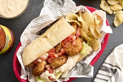 Overhead view of a shrimp po' boy in a basket with potato chips