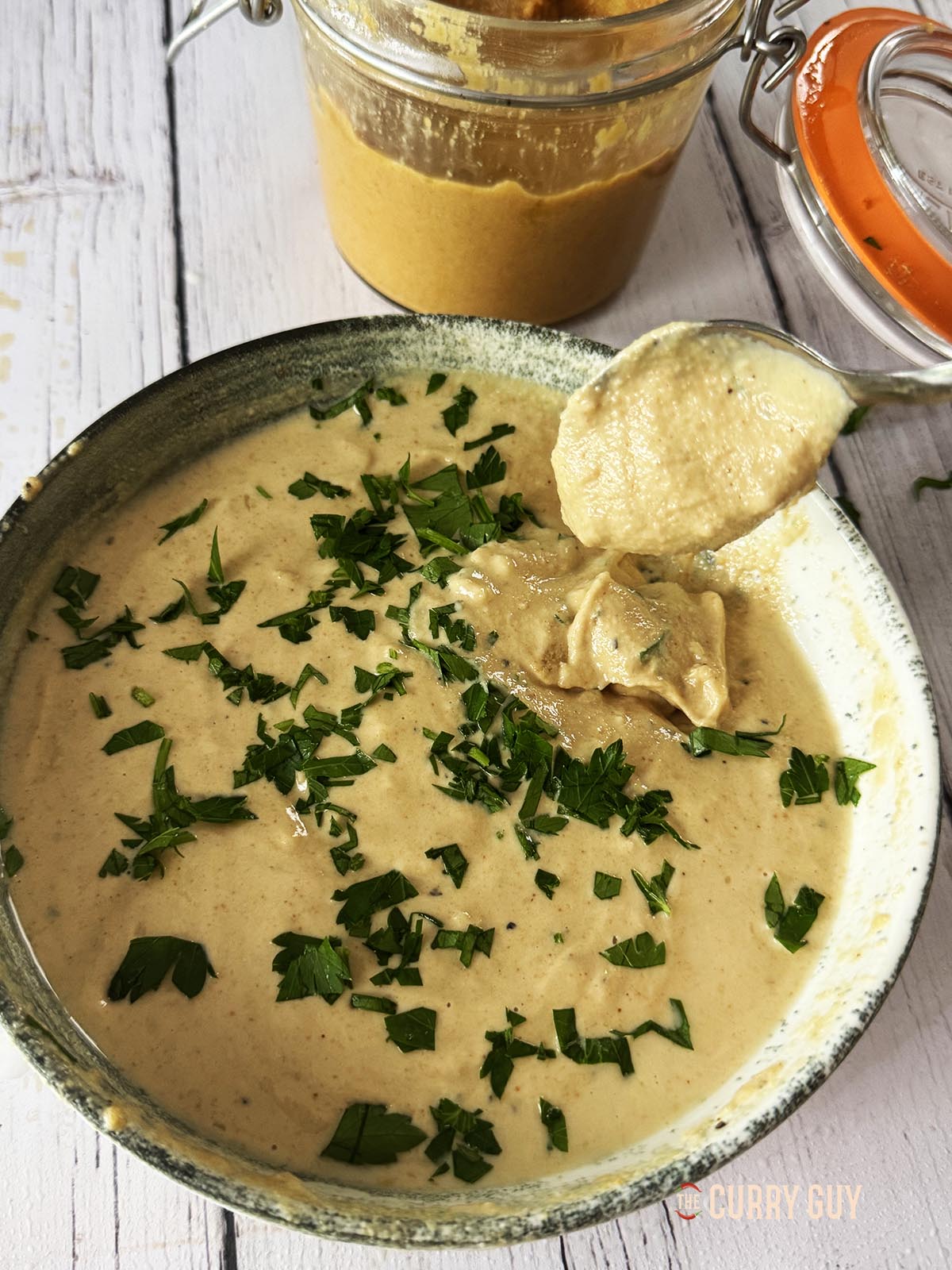 Tahini-Sauce in einer Servierschüssel. Ein Löffel zeigt die dicke Konsistenz der Sauce.