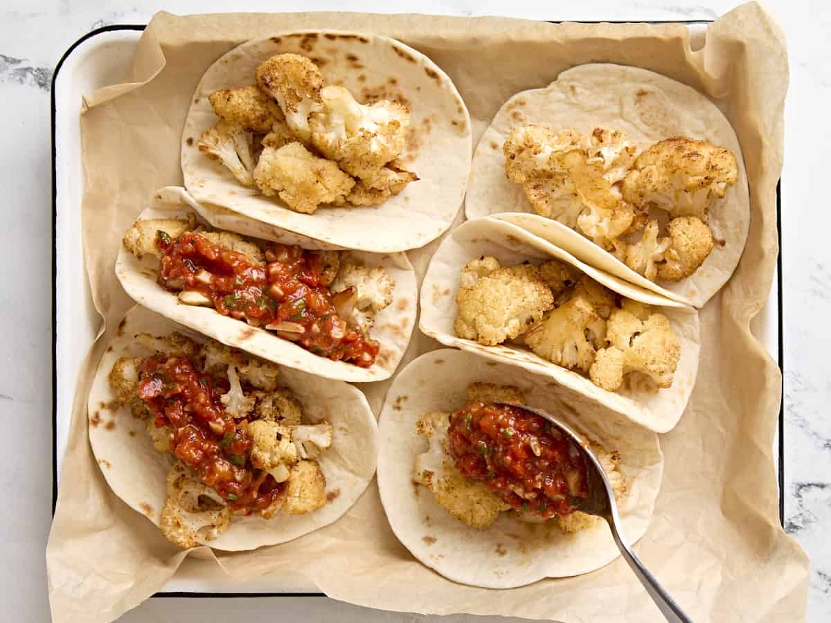 Blumenkohl-Tacos mit Romesco-Sauce auf einem mit Backpapier ausgelegten Backblech