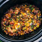 Crockpot Cowboy Casserole with freshly grated and melted cheese on top, still in the crockpot.