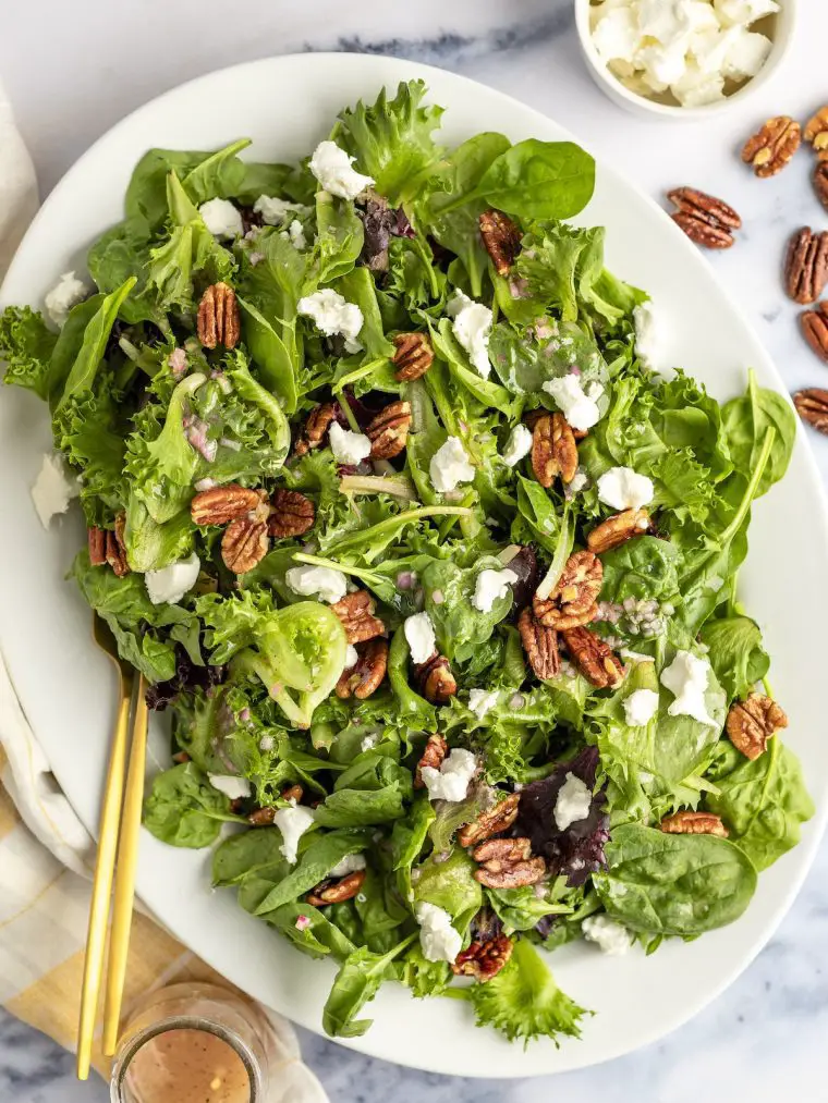 Grüner Salat mit Ziegenkäse, Pekannüssen mit Ahornglasur und Ahorn-Dijon-Vinaigrette mit gestreifter Leinenserviette