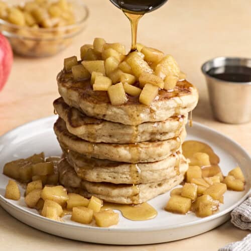 Ein Stapel Apfel-Zimt-Pfannkuchen, obendrüber mit Ahornsirup beträufelt.