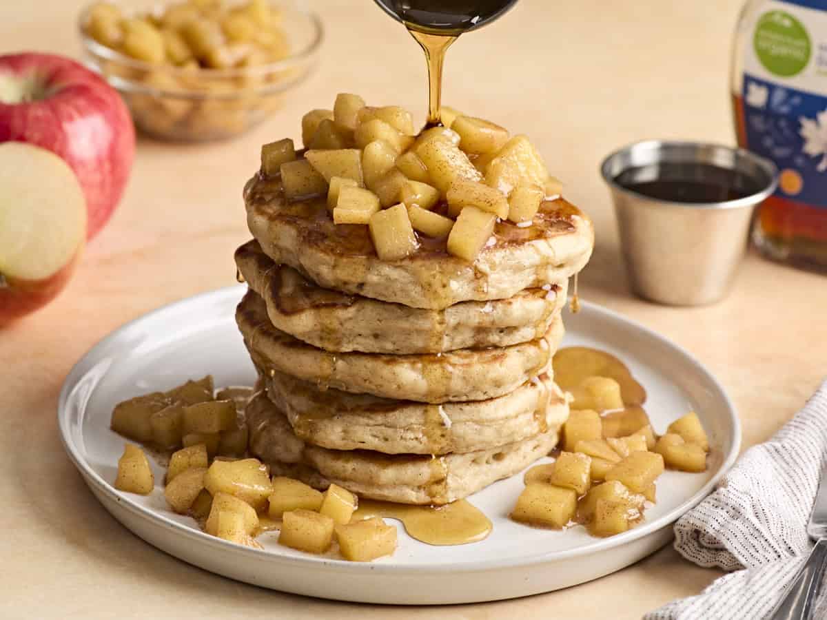 Ein Stapel Apfel-Zimt-Pfannkuchen, obendrüber mit Ahornsirup beträufelt.