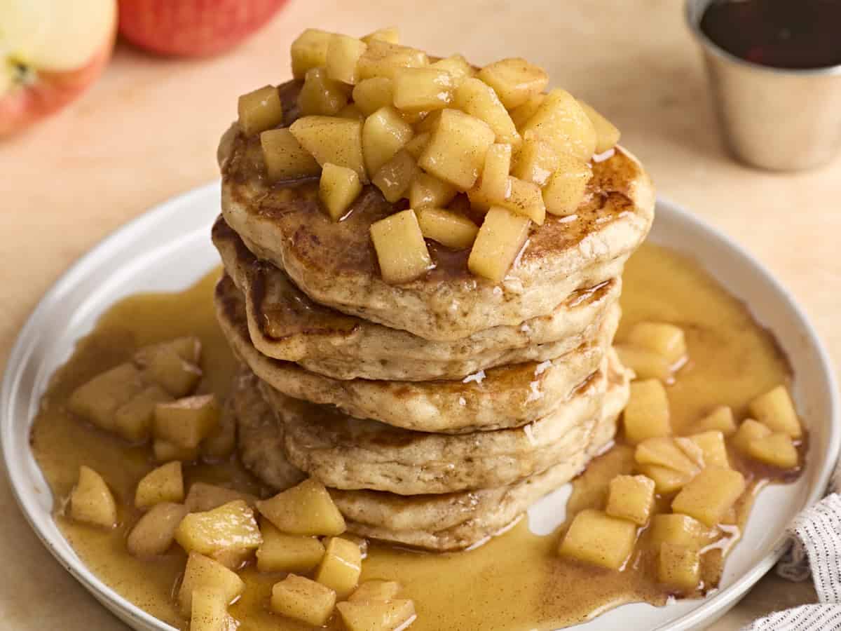 Ein Stapel Apfel-Zimt-Pfannkuchen, obendrüber gegossen mit Ahornsirup.