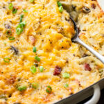 serving spoon in cheesy ham and hash brown casserole