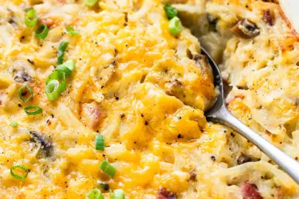 serving spoon in cheesy ham and hash brown casserole