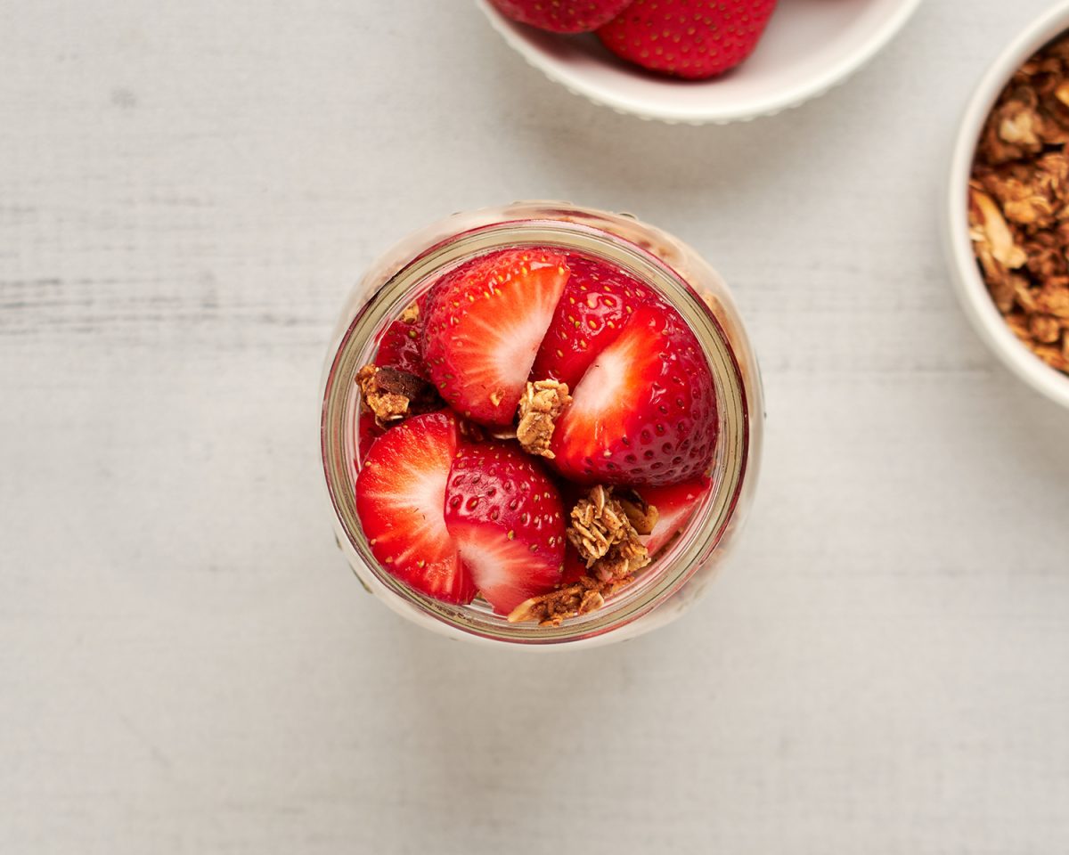 kleines Glas mit Overnight Oats, garniert mit frischen Erdbeeren