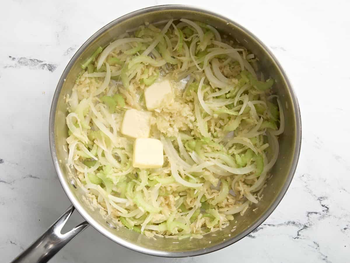 Butter und Knoblauch in eine Pfanne mit Sellerie, Zwiebeln und Pastinake geben