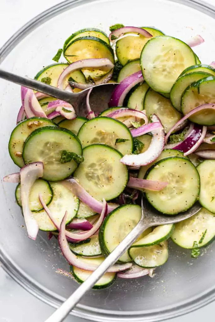 Mediterraner Gurkensalat in einer großen Schüssel mischen