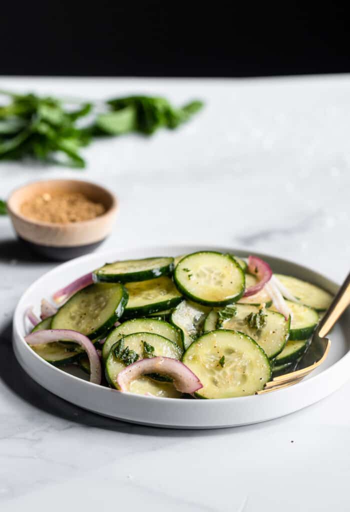 eine Schüssel mediterranen Gurkensalat auf einem Tisch mit Gewürzen