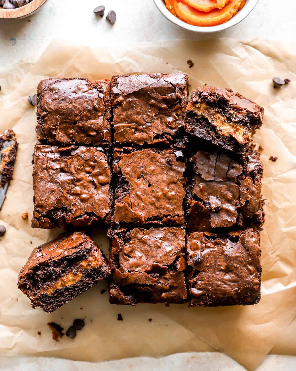 Draufsicht auf geschnittene Kürbis-Brownies auf Pergamentpapier.