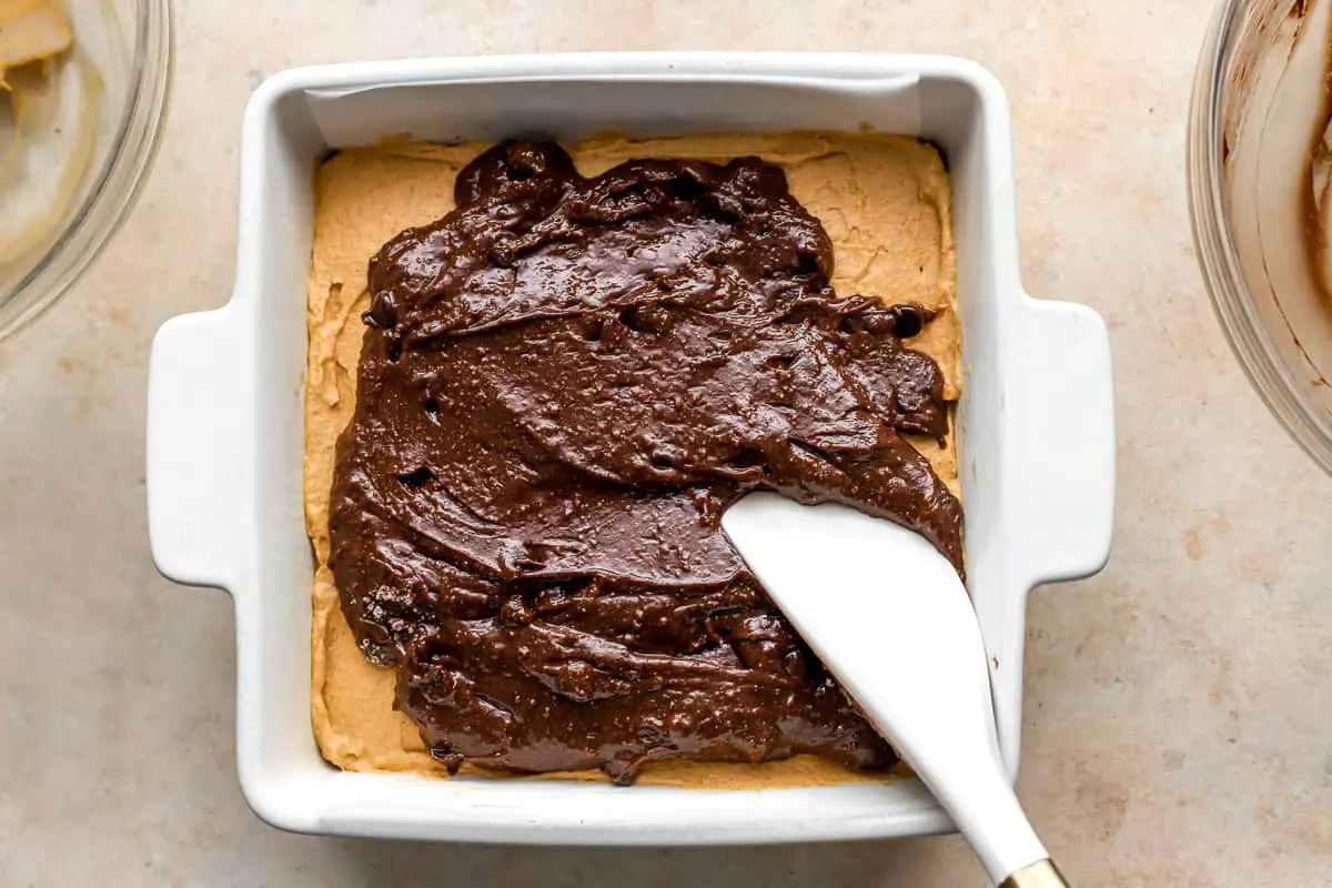 Brownie-Teig darüber verteilen. Kürbisfüllung über den Brownie-Teig in einer quadratischen Auflaufform verteilen.