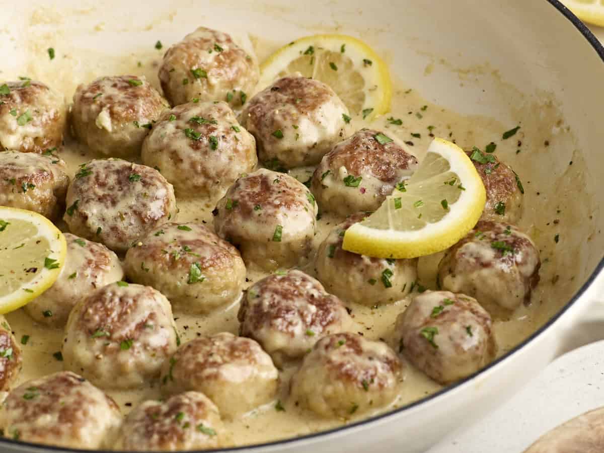 Seitenansicht von Hähnchenfleischbällchen in einer großen Bratpfanne mit Sahnesauce.