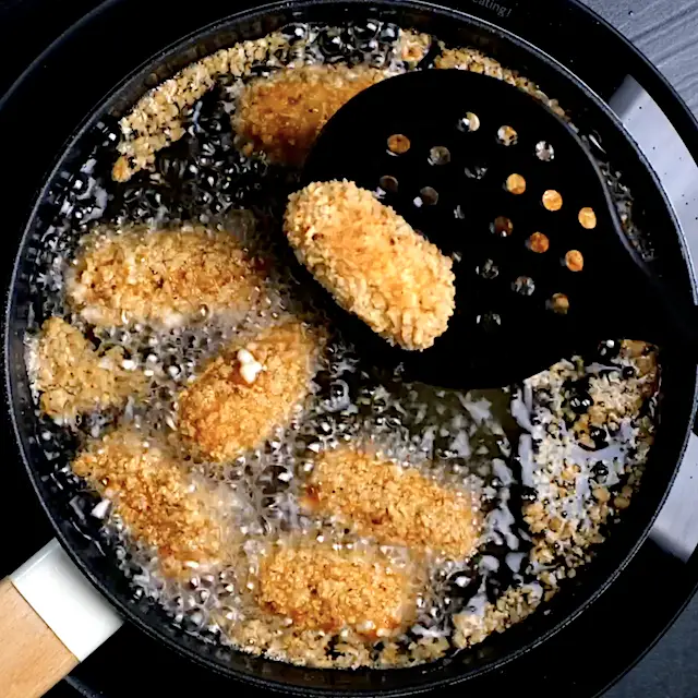 Hausgemachte Mozzarella-Sticks werden in einem Topf in Öl frittiert.