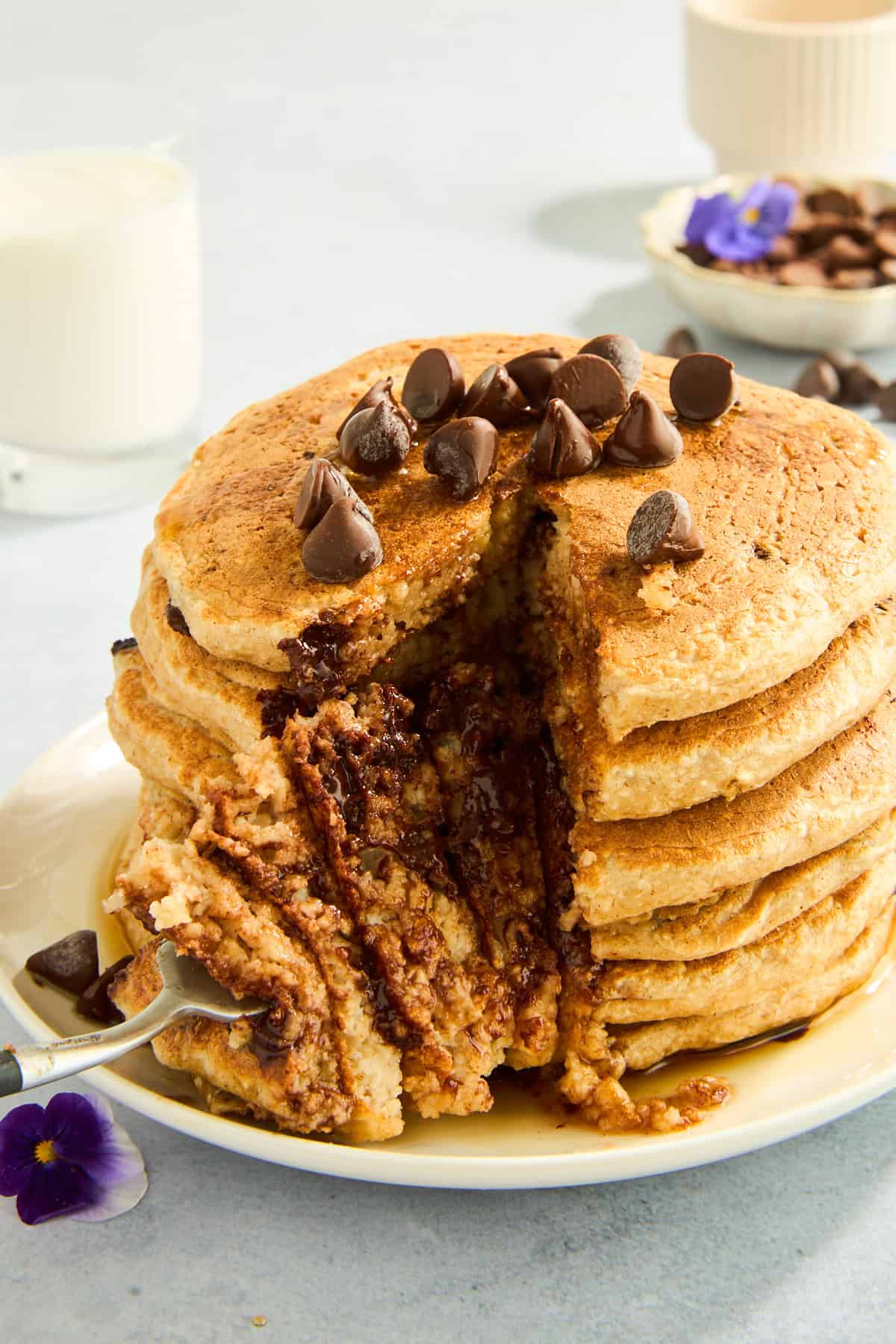 Ein Stapel Protein-Pfannkuchen mit Schokoladenstückchen und einer Gabel, in der ein Bissen steckt. 