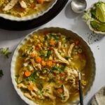 A bowl of homemade chicken noodle soup with a spoon sticking out.