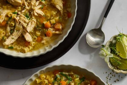 A bowl of homemade chicken noodle soup with a spoon sticking out.