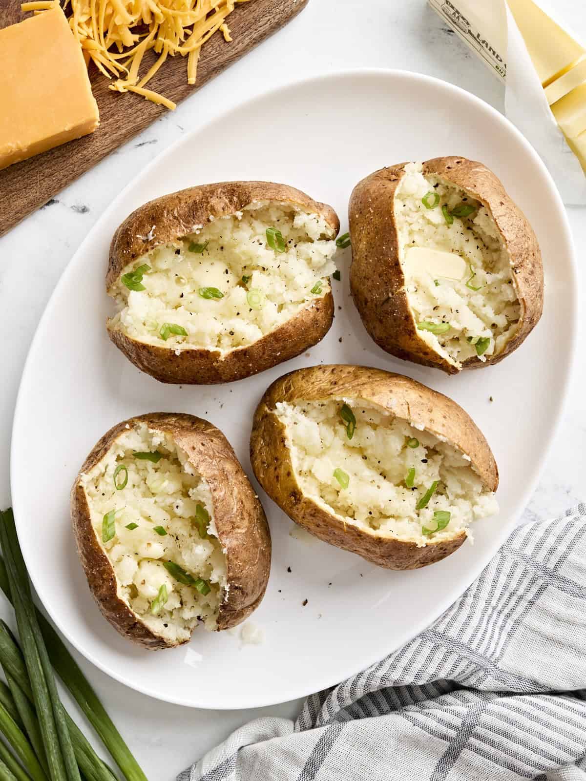 Draufsicht auf im Airfryer gebackene Kartoffeln mit Belag auf einer weißen Platte.