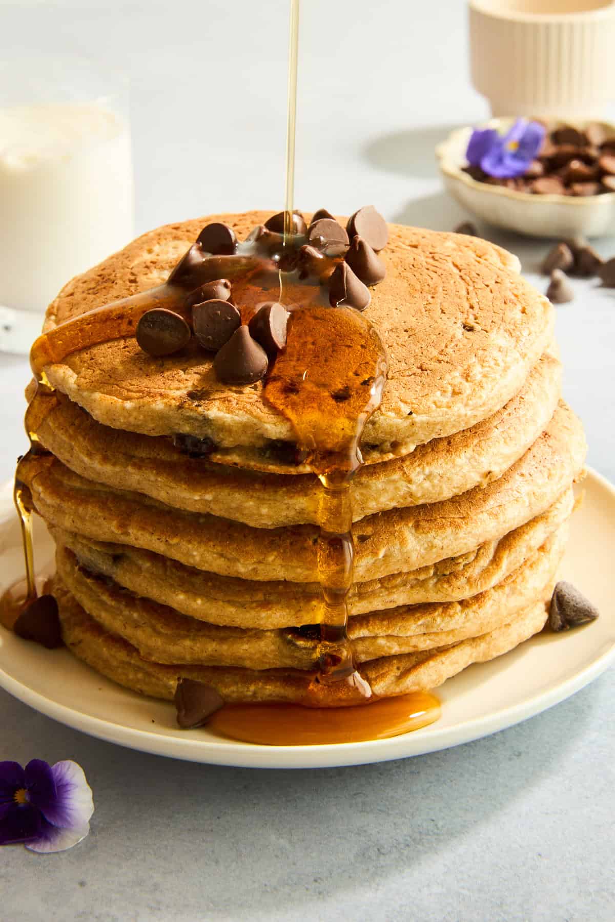 Ein Stapel Protein-Schokoladenchip-Pfannkuchen, garniert mit Schokoladenstückchen und Sirup. 