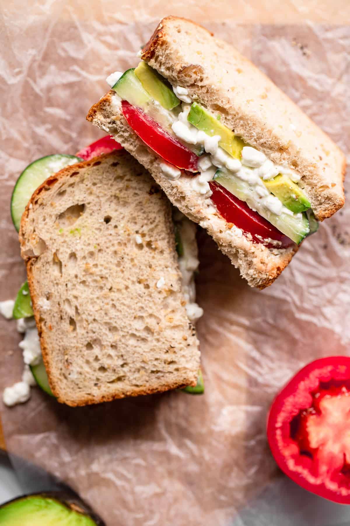 Nahaufnahme eines halbierten Hüttenkäsesandwichs mit Tomaten an der Seite