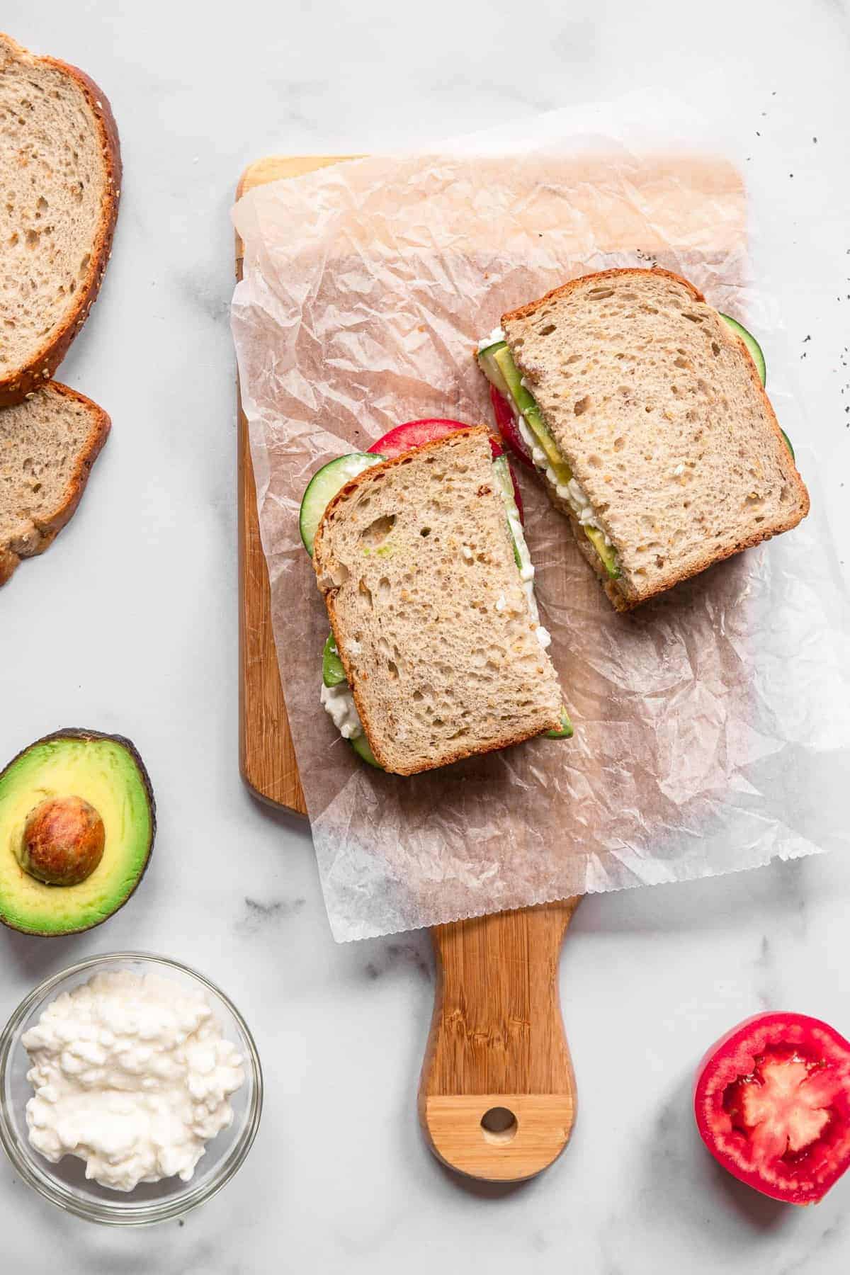 Draufsicht auf Hüttenkäse-Sandwich auf einem Schneidebrett mit Belag an der Seite