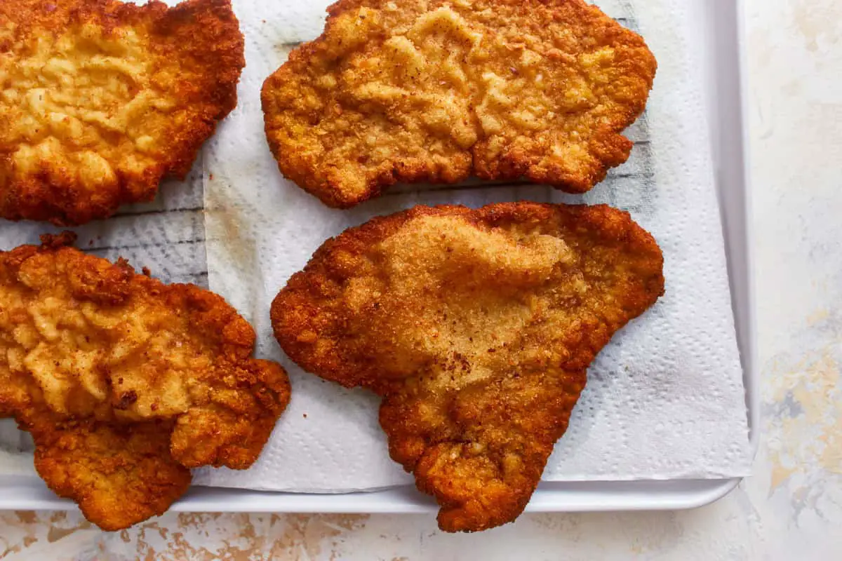 Schweineschnitzel auf Küchenpapier abtropfen lassen.